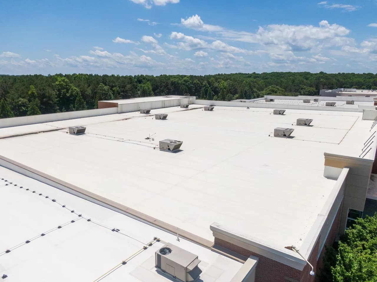Aerial view of a flat white membrane commercial roof with rooftop HVAC units